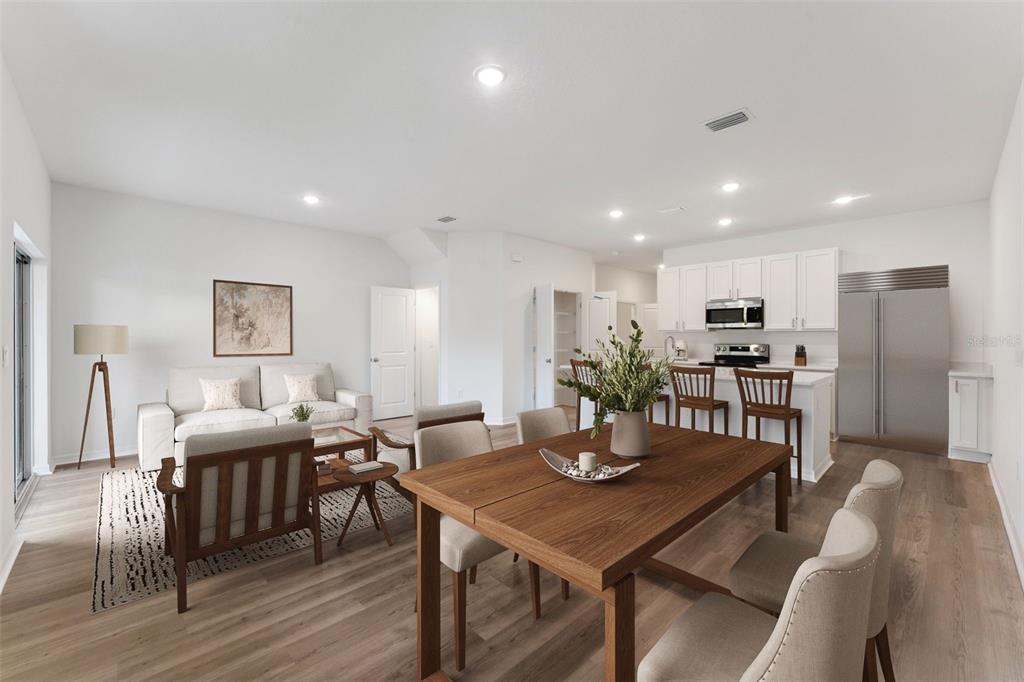 An open-concept living and dining area features light wood floors, white cabinetry, and modern furniture — 646 CEDAR ELM COURT, EUSTIS, FL