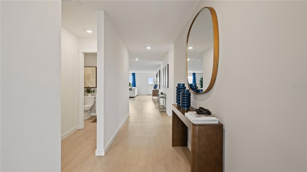 A hallway features light wood flooring, a console table with a mirror, and a bathroom entrance — 6111 SWAMP BAY DRIVE, EDGEWATER, FL