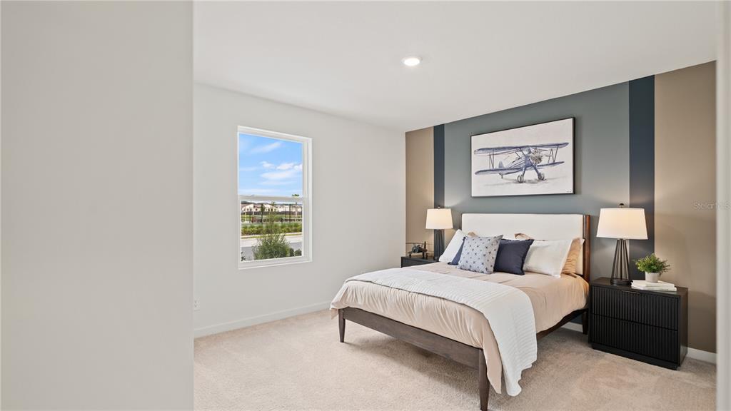 A bedroom features a bed with a blue-and-tan accent wall and a framed airplane print — 6111 SWAMP BAY DRIVE, EDGEWATER, FL
