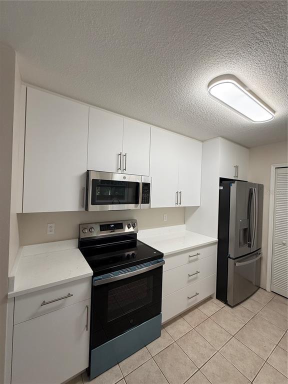 A kitchen features white cabinets, stainless steel appliances, and light-colored countertops — 5454 BRACKEN COURT, WINTER PARK, FL