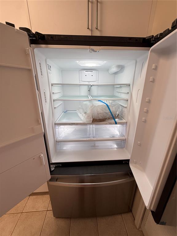 An open stainless steel refrigerator with glass shelves and drawers sits in a kitchen — 5454 BRACKEN COURT, WINTER PARK, FL