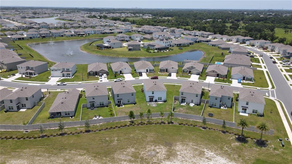 An aerial view shows a suburban neighborhood with houses surrounding a central retention pond — 6330 DISTANT HAZE PLACE, PALMETTO, FL