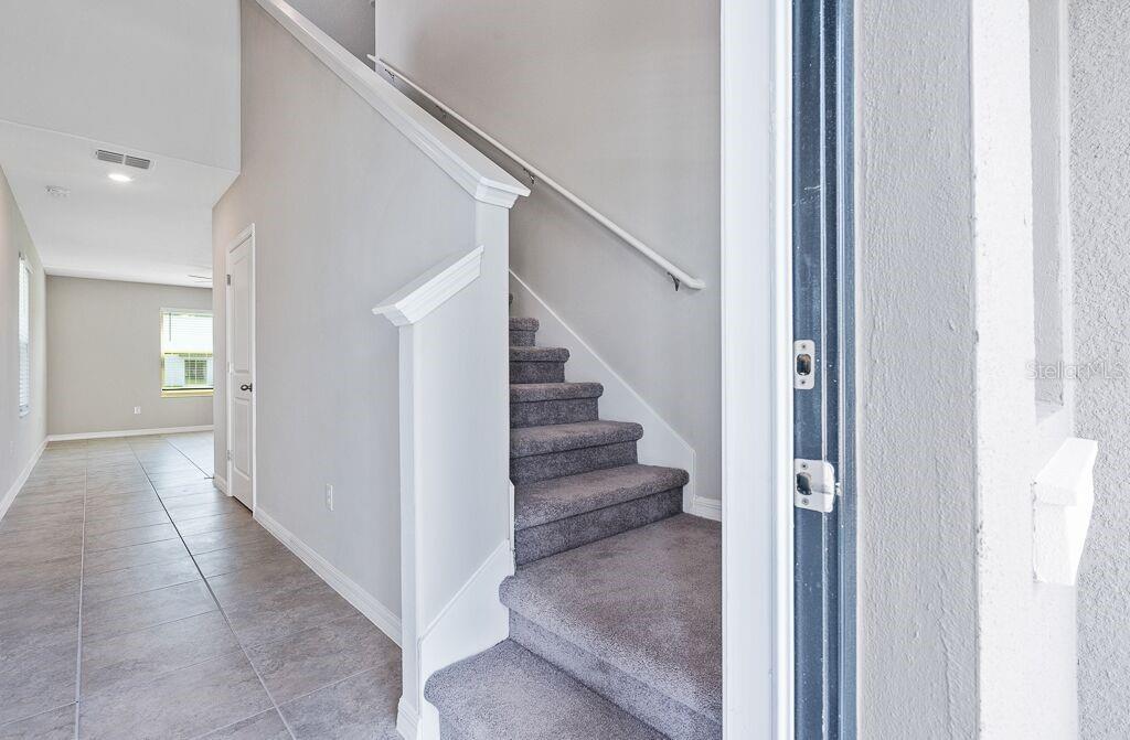 A carpeted staircase with a white railing sits next to a tiled hallway — 7229 SALT RIVER AVENUE, SUN CITY CENTER, FL