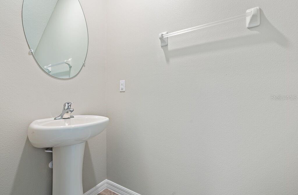 A bathroom features a white pedestal sink, an oval mirror, and a towel bar — 7229 SALT RIVER AVENUE, SUN CITY CENTER, FL