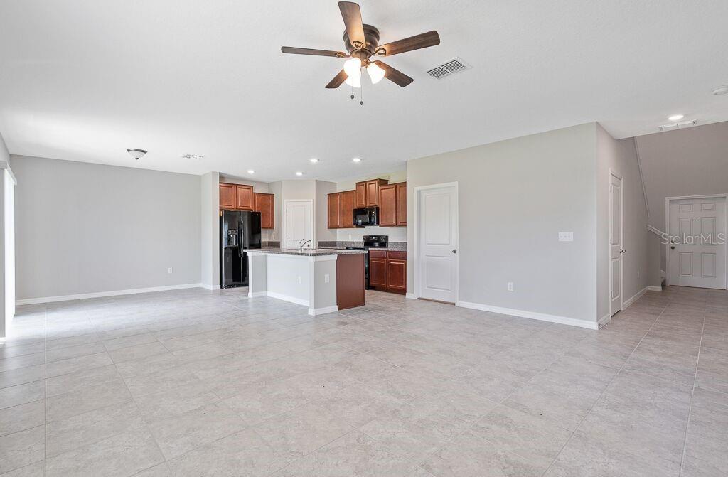 An open-concept kitchen with dark wood cabinets and a center island overlooks a tiled living area — 7229 SALT RIVER AVENUE, SUN CITY CENTER, FL