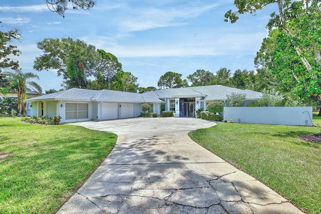 A single-story house with a large concrete driveway, a three-car garage, and surrounding green lawn — 2307 FAIRWAY LANE, SEBRING, FL