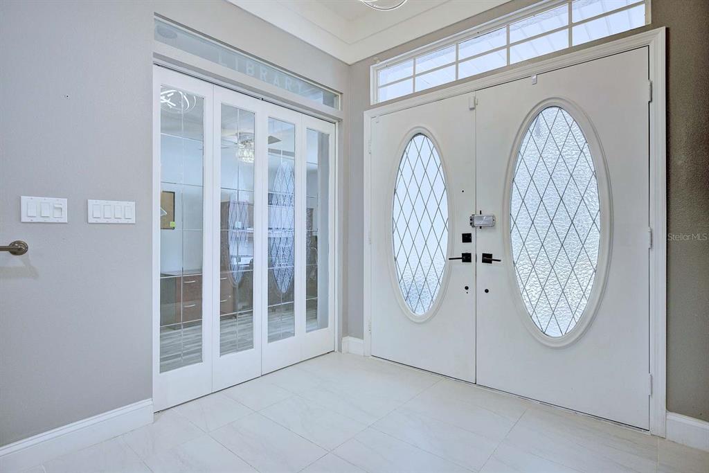 A bright entryway features white tile floors, double front doors, and glass-paneled French doors — 2307 FAIRWAY LANE, SEBRING, FL