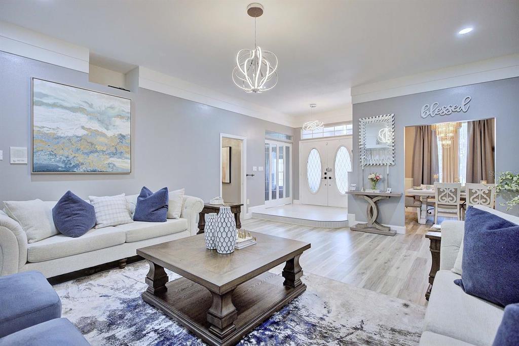 A living room features light gray walls, wood-look flooring, a large area rug, and modern lighting — 2307 FAIRWAY LANE, SEBRING, FL