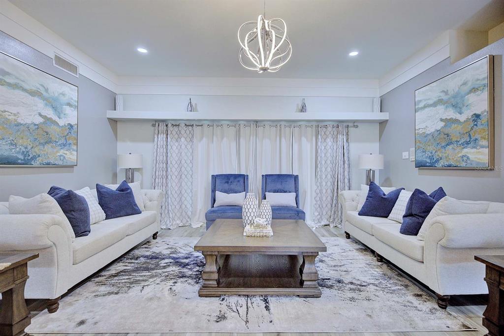 A symmetrical living room features two white sofas, two blue chairs, and a central coffee table — 2307 FAIRWAY LANE, SEBRING, FL