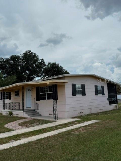 A single-story light-colored mobile home features a front porch with black metal railings — 1730 HUNTINGTON STREET, LAKELAND, FL
