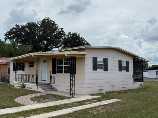 A light-colored single-story house with a covered front porch and black shutters — 1730 HUNTINGTON STREET, LAKELAND, FL