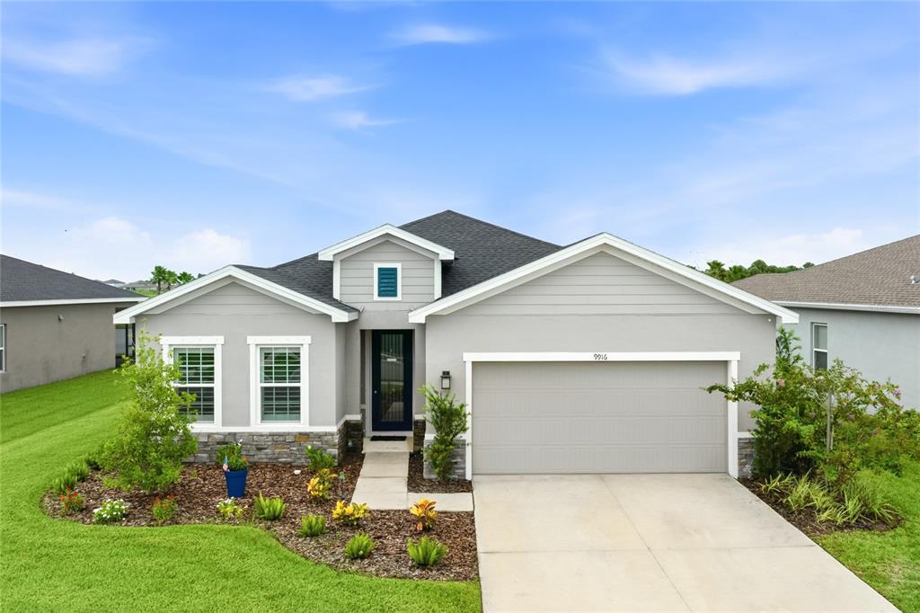 A single-story house with gray siding, a stone base, and a two-car garage — 9916 DAYBREAK GLEN, PARRISH, FL