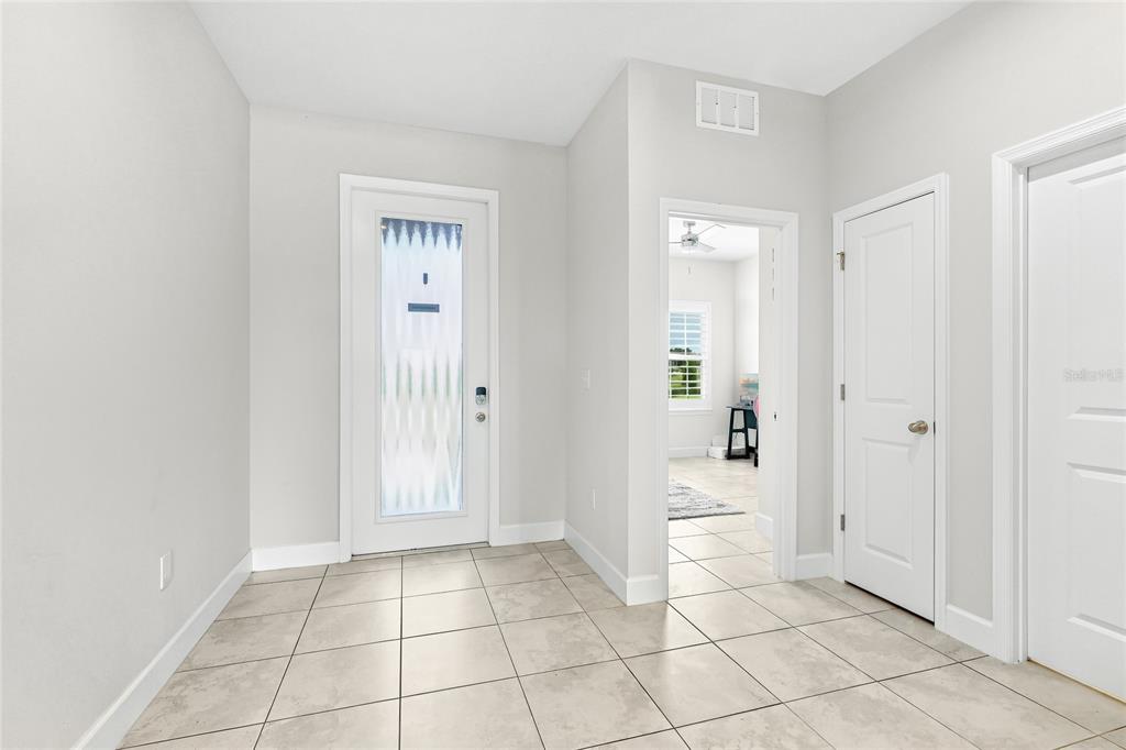 An entryway with light tile flooring, a glass-paneled front door, and two interior doors — 9916 DAYBREAK GLEN, PARRISH, FL