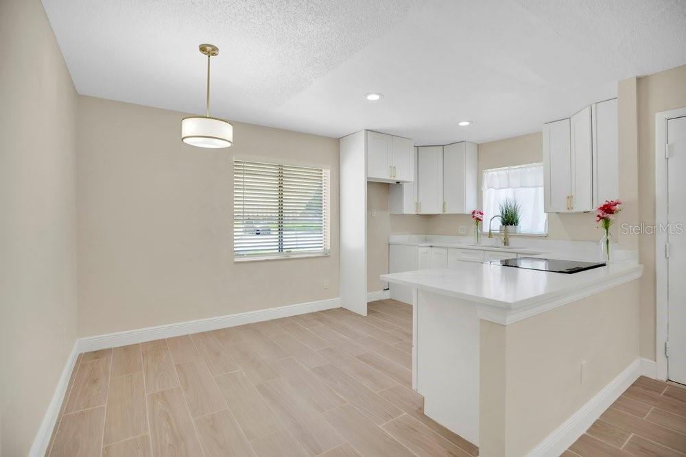 A kitchen and dining area with white cabinets, light wood-look flooring, and a pendant light — 4410 WATCH HILL ROAD, ORLANDO, FL