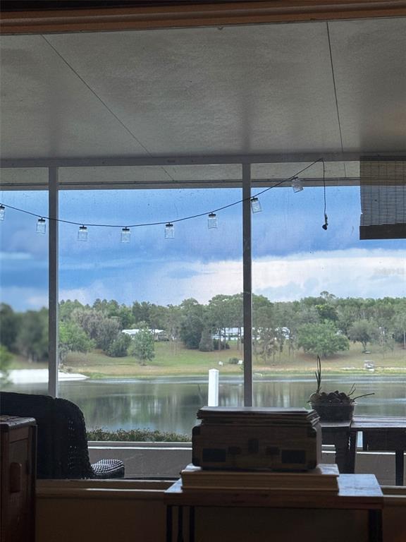 A view of a lake and trees through a windowed sunroom with string lights — 10615 SE 142ND AVENUE ROAD, OCKLAWAHA, FL