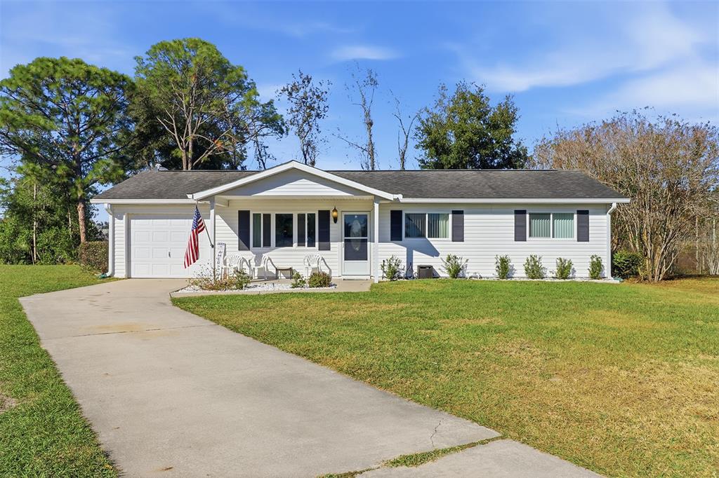 A single-story house with white siding, a concrete driveway, and a front lawn — 8571 SW 105TH PLACE, OCALA, FL