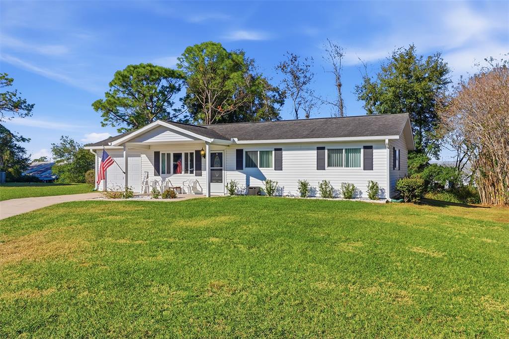 A single-story white house with a covered porch, dark shutters, and a large front lawn — 8571 SW 105TH PLACE, OCALA, FL
