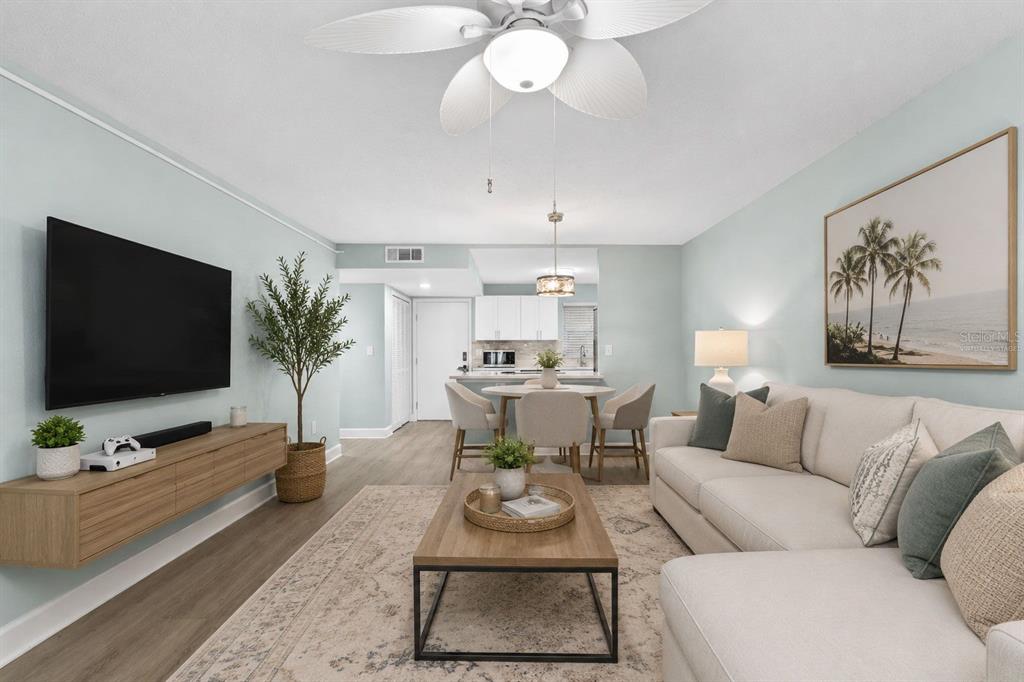 A living room with a sectional sofa, television, dining area, and light blue walls — 17035 GULF BOULEVARD UNIT 116, NORTH REDINGTON BEACH, FL
