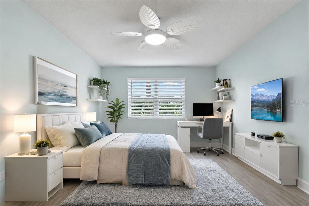 A bedroom with light blue walls, a bed, a desk, and a ceiling fan — 17035 GULF BOULEVARD UNIT 116, NORTH REDINGTON BEACH, FL
