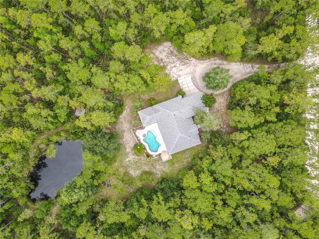 An aerial view of a blue house with a swimming pool surrounded by dense forest — 3441 HICKORY CREEK ROAD, DELTONA, FL