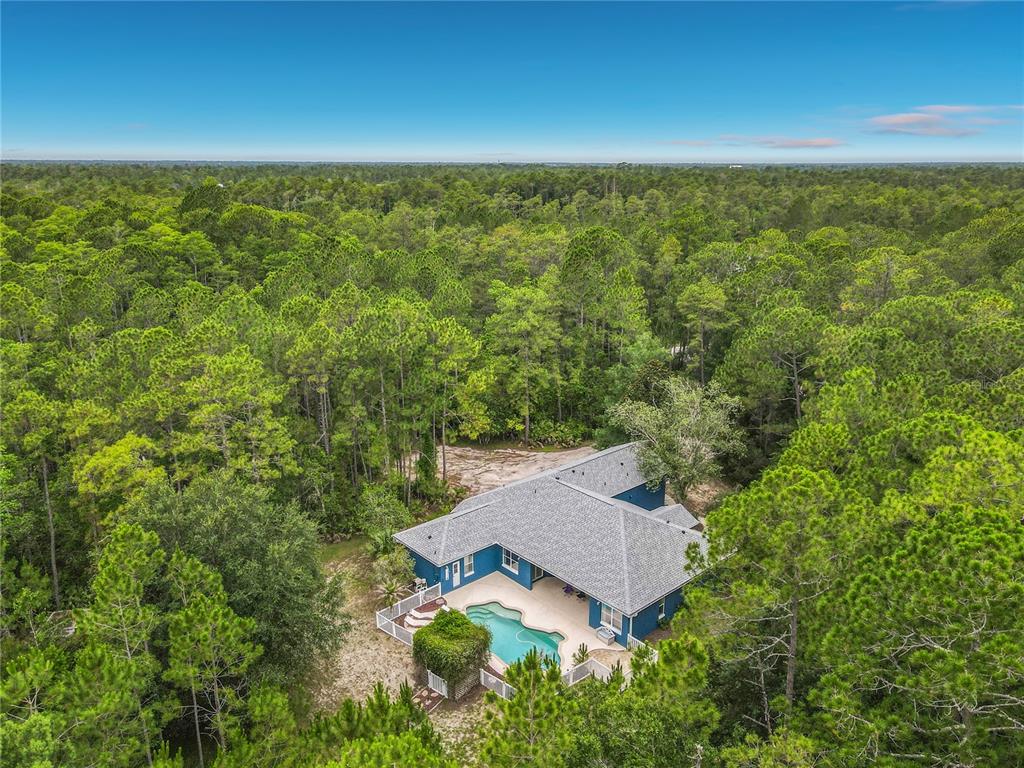 An aerial view of a blue house with a swimming pool and fenced backyard — 3441 HICKORY CREEK ROAD, DELTONA, FL