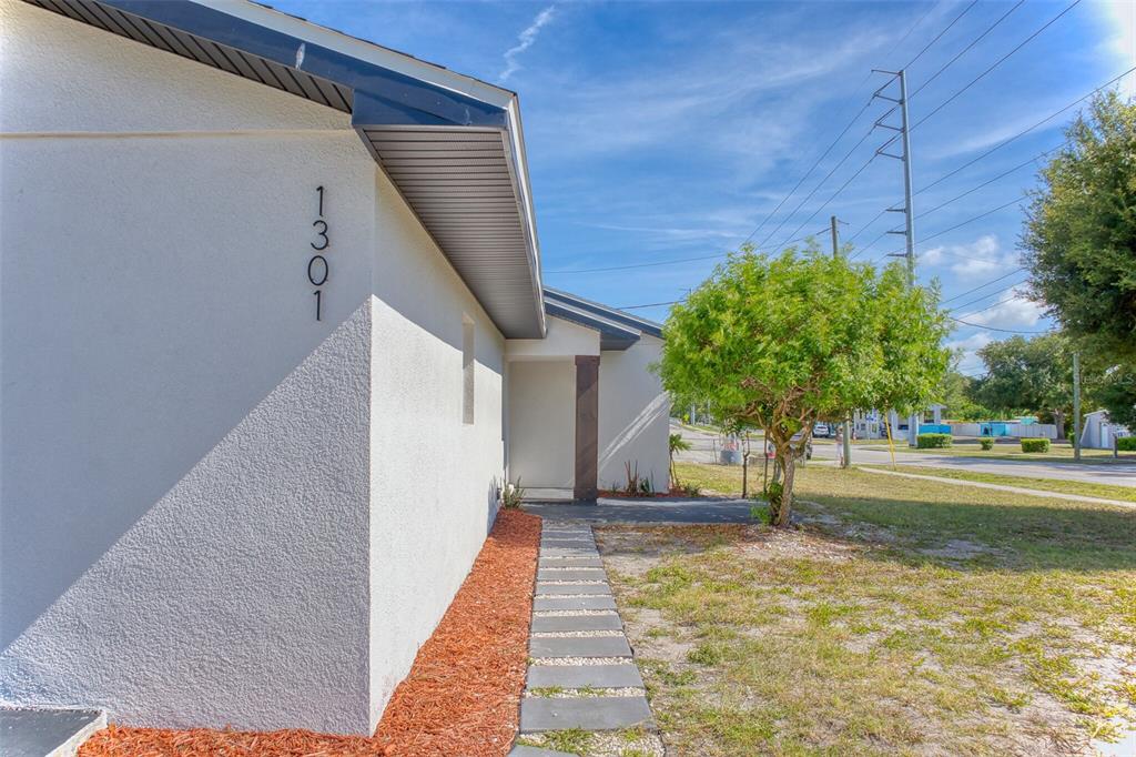 A side view of a white house exterior with a stone walkway and house number 1301 — 1301 WOODBINE STREET, CLEARWATER, FL