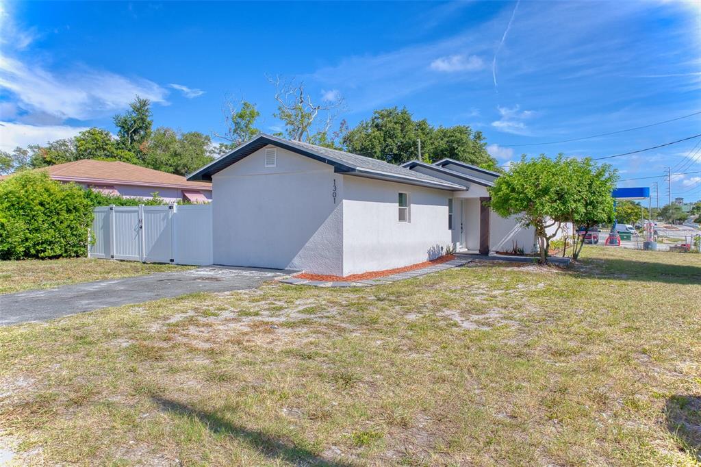 A single-story house with a light-colored exterior, a driveway, and a white privacy fence — 1301 WOODBINE STREET, CLEARWATER, FL