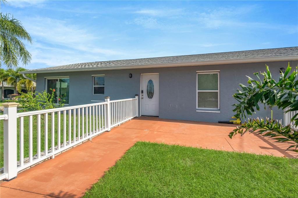 A gray house exterior features a white front door, a white railing, and a patio — 2054 SAFFOLD PARK DRIVE, RUSKIN, FL
