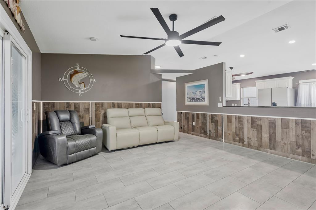 A living room features a wall-mounted television, a fireplace, wood-look wainscoting, and sliding glass doors — 2054 SAFFOLD PARK DRIVE, RUSKIN, FL