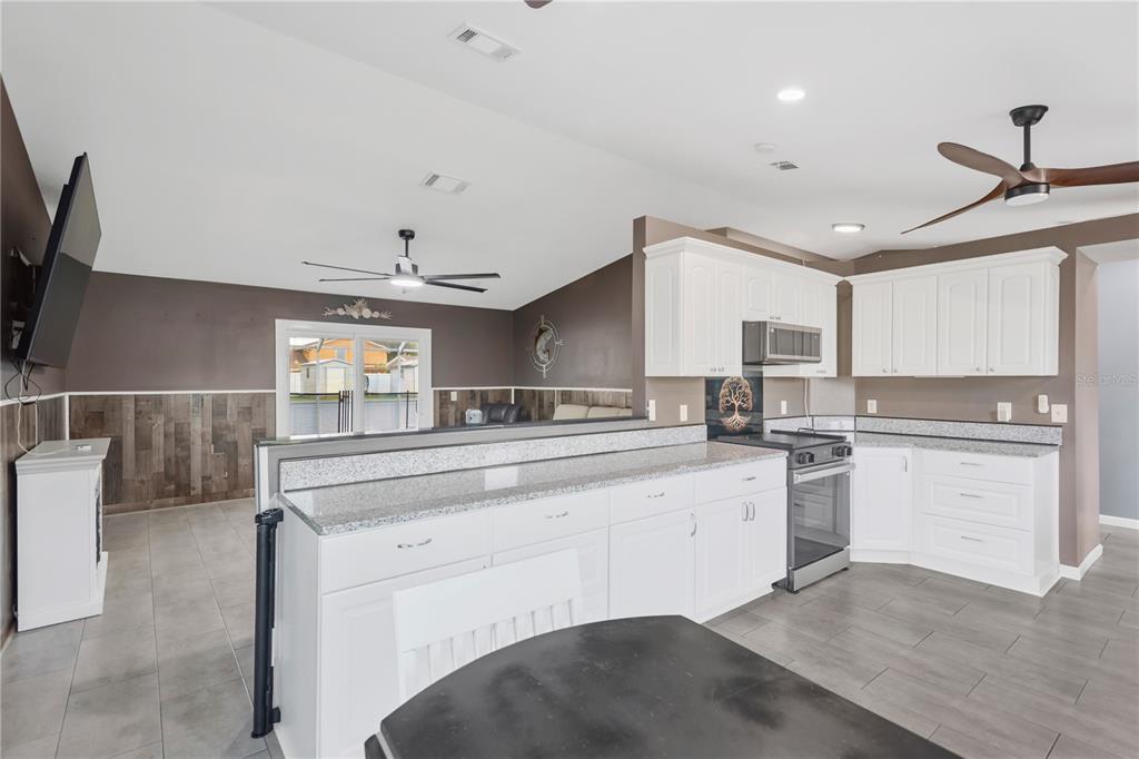 A living room features gray tile floors, wood-paneled wainscoting, a recliner, and a light-colored sofa — 2054 SAFFOLD PARK DRIVE, RUSKIN, FL