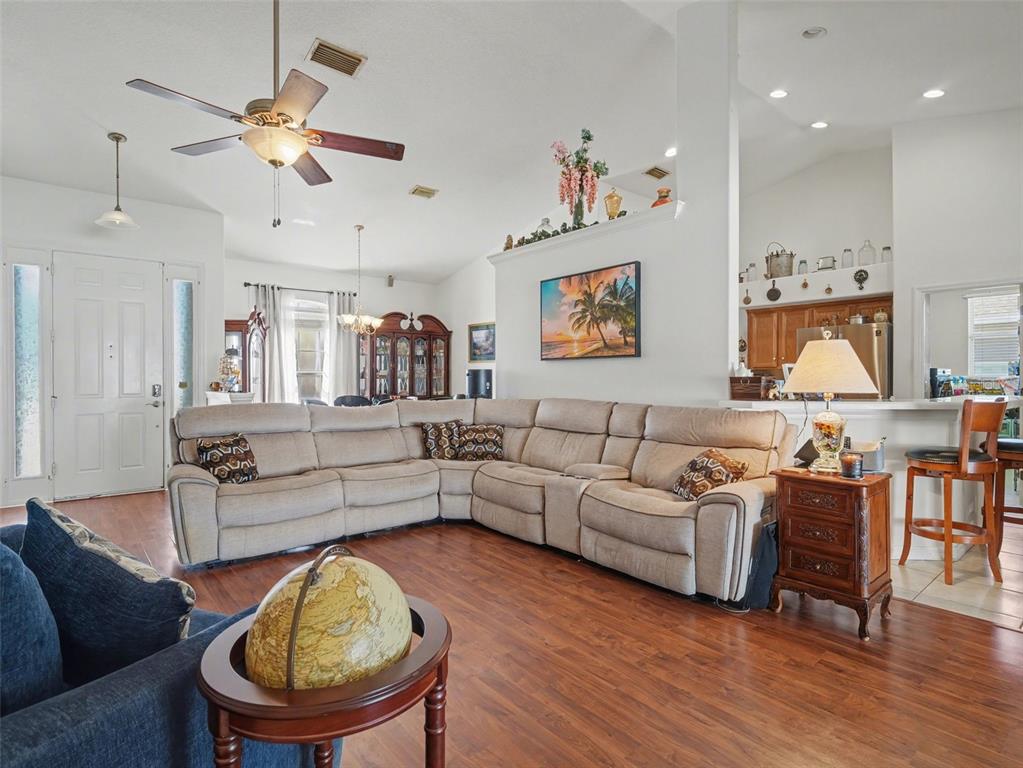 A living room with wood-look flooring, a ceiling fan, and sliding glass doors to a pool — 535 PLANTERS MANOR WAY, BRADENTON, FL