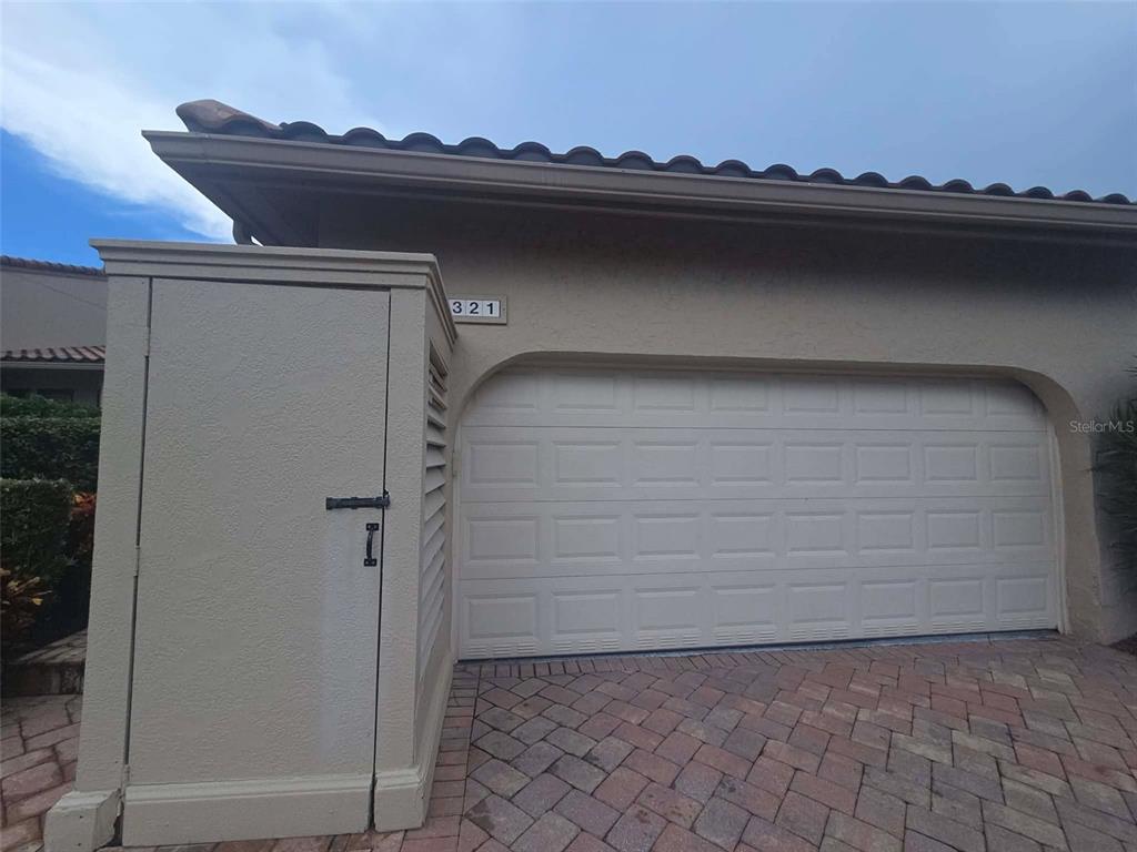 A beige garage door and an adjacent storage unit are set against a stucco exterior — 2321 HARBOUR OAKS DRIVE, LONGBOAT KEY, FL