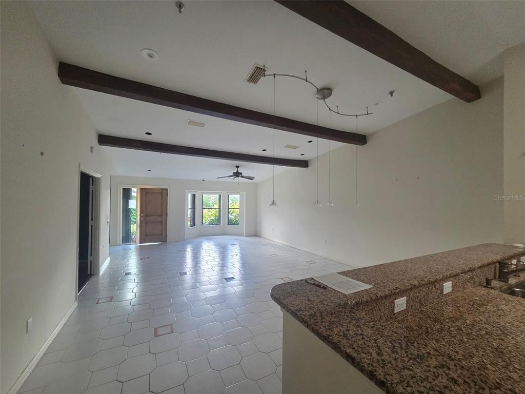 An open-concept living area features tile flooring, exposed wooden ceiling beams, and a granite countertop — 2321 HARBOUR OAKS DRIVE, LONGBOAT KEY, FL