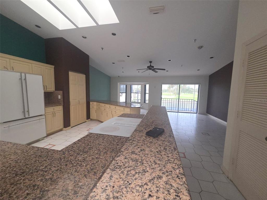 A kitchen with granite countertops and light-colored cabinets overlooks a living area with tile floors — 2321 HARBOUR OAKS DRIVE, LONGBOAT KEY, FL