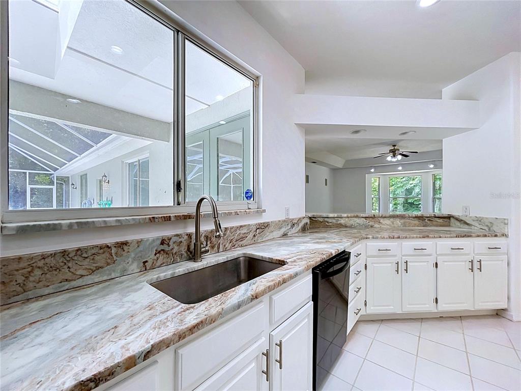 A kitchen features white cabinets, a stainless steel sink, and patterned stone countertops — 464 E LIBERTY STREET, HERNANDO, FL