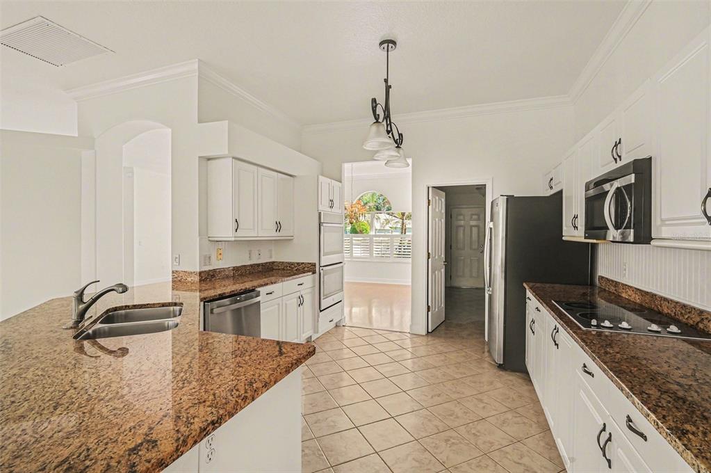 A kitchen with white cabinets, granite countertops, stainless steel appliances, and tile flooring — 8 FOX CLIFF WAY, ORMOND BEACH, FL