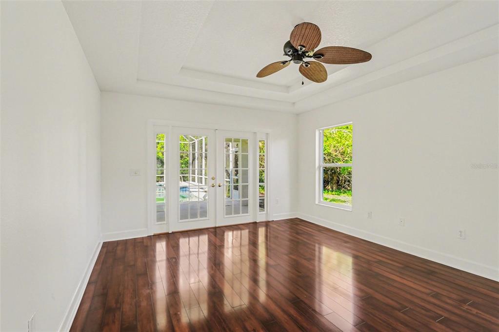 An empty room with dark wood floors, a tray ceiling, ceiling fan, and French doors — 8 FOX CLIFF WAY, ORMOND BEACH, FL