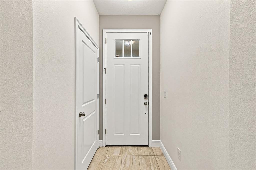 A white front door with a glass window insert stands in a tiled entryway — 17871 STELLA MOON PLACE, LUTZ, FL