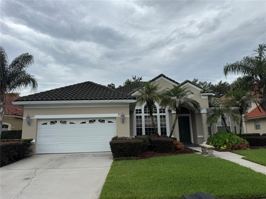 A single-story house with a two-car garage, tile roof, and palm trees in the front yard — 14444 DOVER FOREST DRIVE, ORLANDO, FL