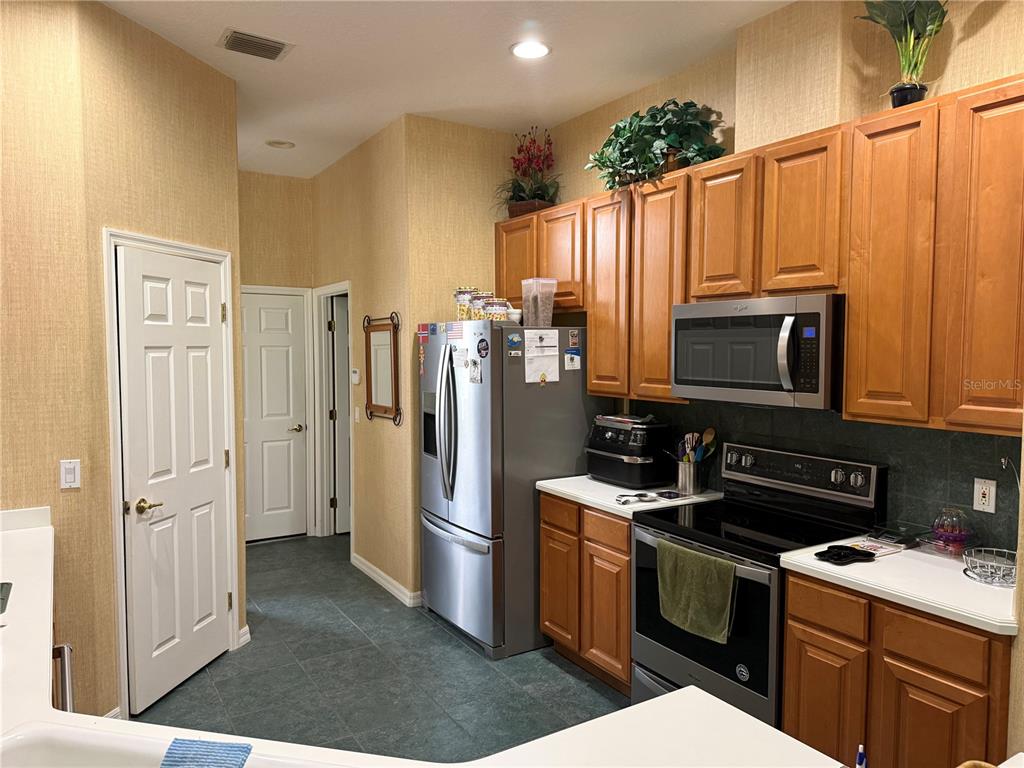 A kitchen features wood cabinets, stainless steel appliances, and tile flooring — 14444 DOVER FOREST DRIVE, ORLANDO, FL