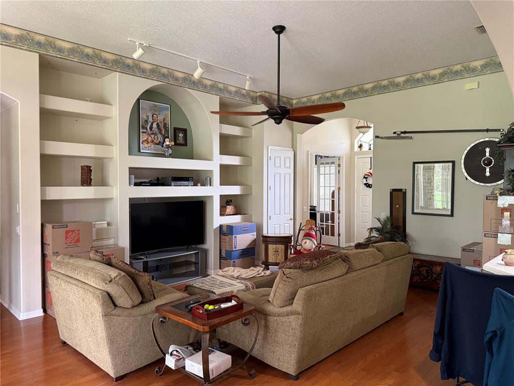 A living room features a built-in entertainment center, a ceiling fan, and hardwood flooring — 14444 DOVER FOREST DRIVE, ORLANDO, FL