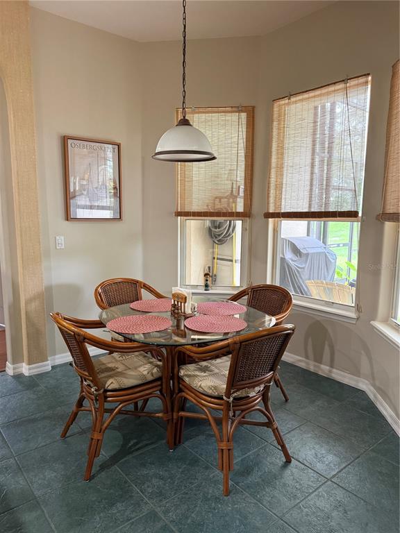 A dining area features a glass-topped rattan table with four chairs under a pendant light — 14444 DOVER FOREST DRIVE, ORLANDO, FL