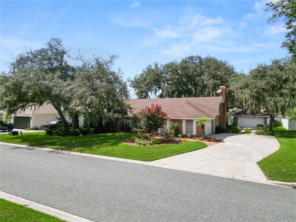 A single-story brick house with a shingled roof, front lawn, and mature trees — 1626 SHERWOOD LAKES BOULEVARD, LAKELAND, FL