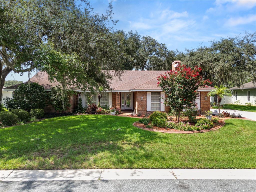 A single-story brick house with a front lawn, landscaping, and a large tree — 1626 SHERWOOD LAKES BOULEVARD, LAKELAND, FL