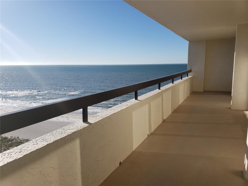 A balcony with a metal railing overlooks the ocean under a clear blue sky — 1460 GULF BOULEVARD UNIT 1102, CLEARWATER, FL