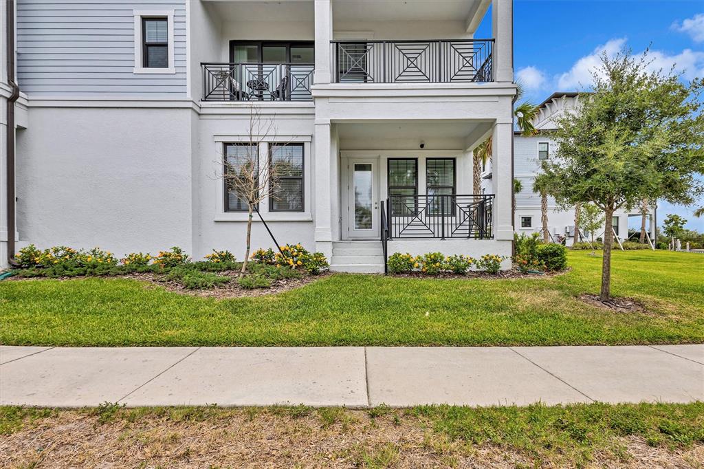 A two-story building exterior features a ground-level patio, a second-story balcony, and landscaping — 3027 BERMUDA SLOOP CIRCLE, RUSKIN, FL