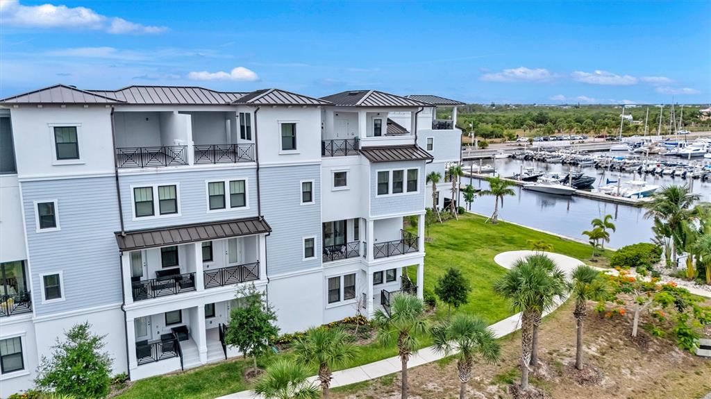 An exterior view of a multi-story apartment building with balconies overlooking a boat marina — 3027 BERMUDA SLOOP CIRCLE, RUSKIN, FL