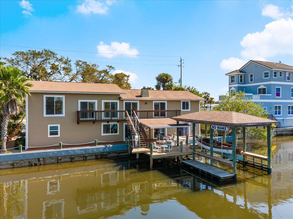 A tan two-story house sits on a canal with a private boat dock and lift — 2306 JOHN ANDERSON DRIVE, ORMOND BEACH, FL