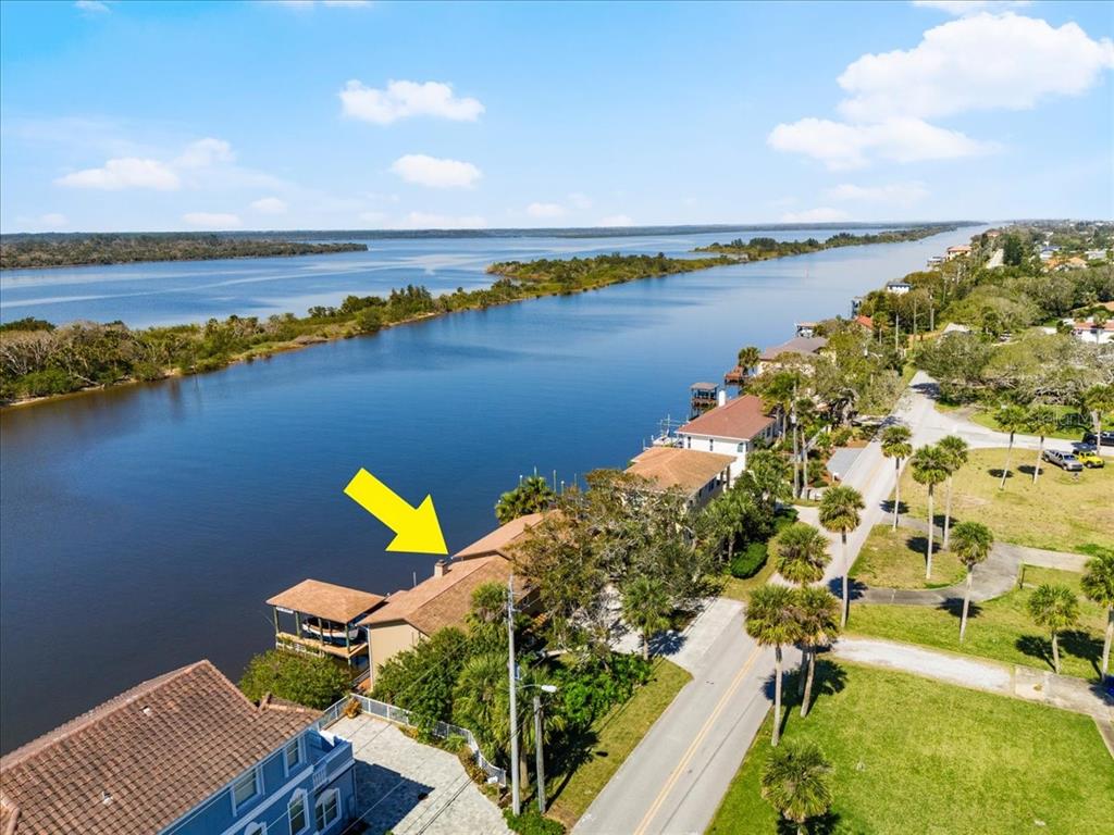 An aerial view shows a waterfront house with a brown roof beside a road — 2306 JOHN ANDERSON DRIVE, ORMOND BEACH, FL