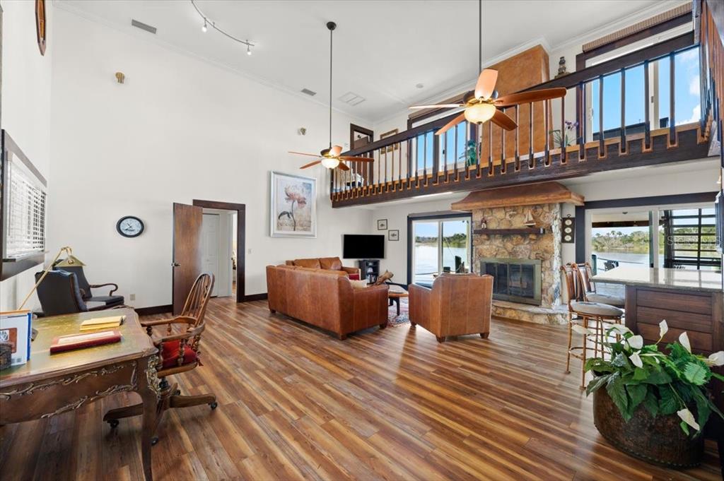 A living room with a stone fireplace, wood floors, and a loft overlooking the space — 2306 JOHN ANDERSON DRIVE, ORMOND BEACH, FL